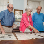 From left, Brian Beck, Mary McWilliams, and Gene Cleveland look over historic photographs inside the Winston home in Tuscumbia.