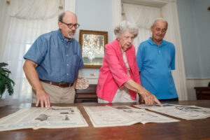 From left, Brian Beck, Mary McWilliams, and Gene Cleveland look over historic photographs inside the Winston home in Tuscumbia.