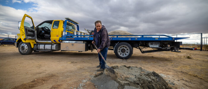 Alfredo Lara prepares cement to reinforce fencing at his new tow yard after his towing business under the 10 Freeway was destroyed.