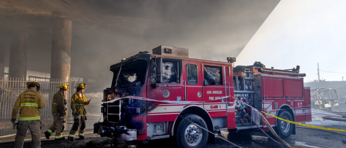 Firefighters look at their Fire Engine 17 that got burned in a pallet fire under the 10 Freeway overpass on Nov. 11, 2023, in Los Angeles.