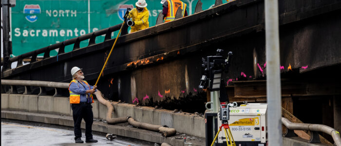 Construction workers take measurements along the burned portion of the 10 Freeway above 14th Street at Alameda on Nov. 15, 2023.