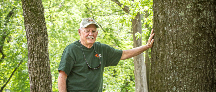 Steve McEachron leans against a large cypress tree while posing for a portrait at Wildwood Park on Wednesday, April 30, 2025, in Florence, Ala.