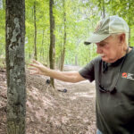 Steve McEachron explains a condition that causes trees to produce living tissue damaging their own bark under certain environmental stress, while walking a trail at Wildwood Park on Wednesday, April 30, 2025, in Florence, Ala.