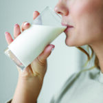 A woman takes a drink of milk.