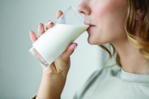 A woman takes a drink of milk.