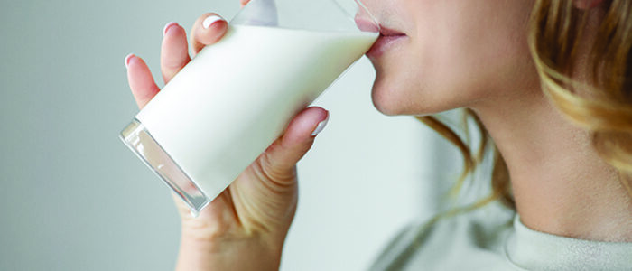 A woman takes a drink of milk.
