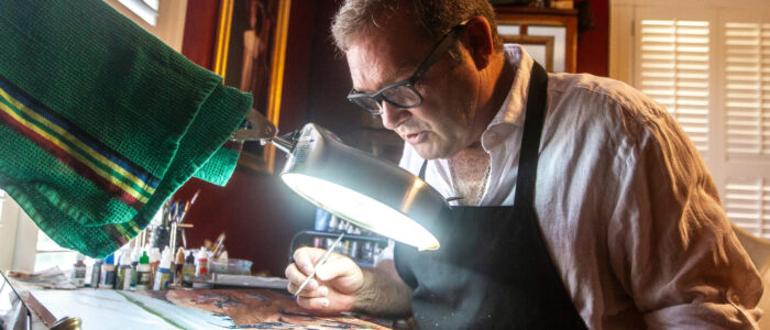 Kurt Vetters leans over a painting in progress.