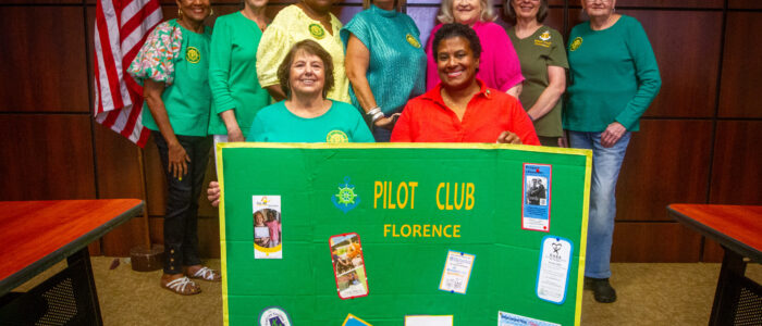 Members of the Florence Pilot Club pose with a display board.