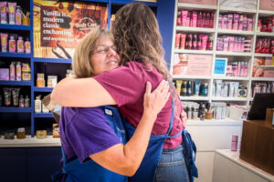 Gloria “Gigi” Broadway hugs a co-worker at Bath & Body Works in Florence.