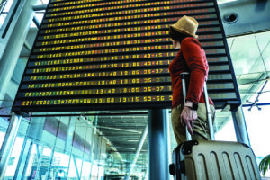 A woman looks at digital arrival and departure board.