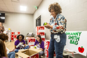 Jeanine Martin works with student volunteers to polish apples during a Junior League of the Shoals’ meeting inside the Handy Recreation Center in Florence. [DAN BUSEY/TIMESDAILY]