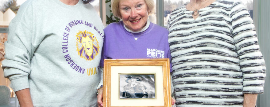 Sabrina Clark, left, Briget McCabe and Neva Bretherick stand together while holding a framed photograph during a visit in Florence.